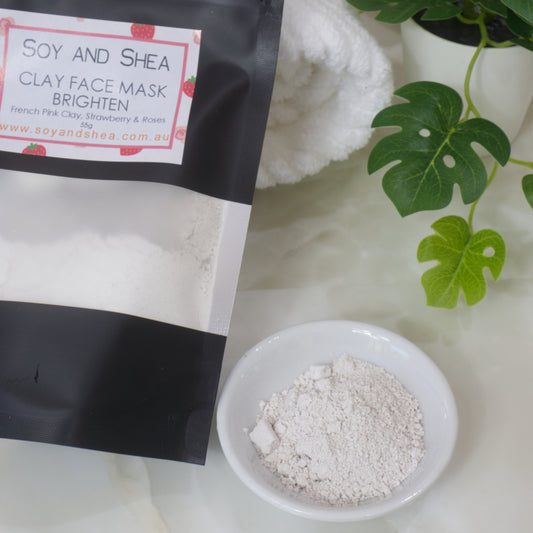 Soy and Shea Clay Face Mask packaging with a bowl of powder on a light background
