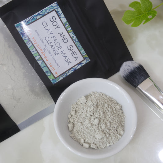 Soy and Shea Clay Face Mask with a brush and bowl of pale green powder on a white background