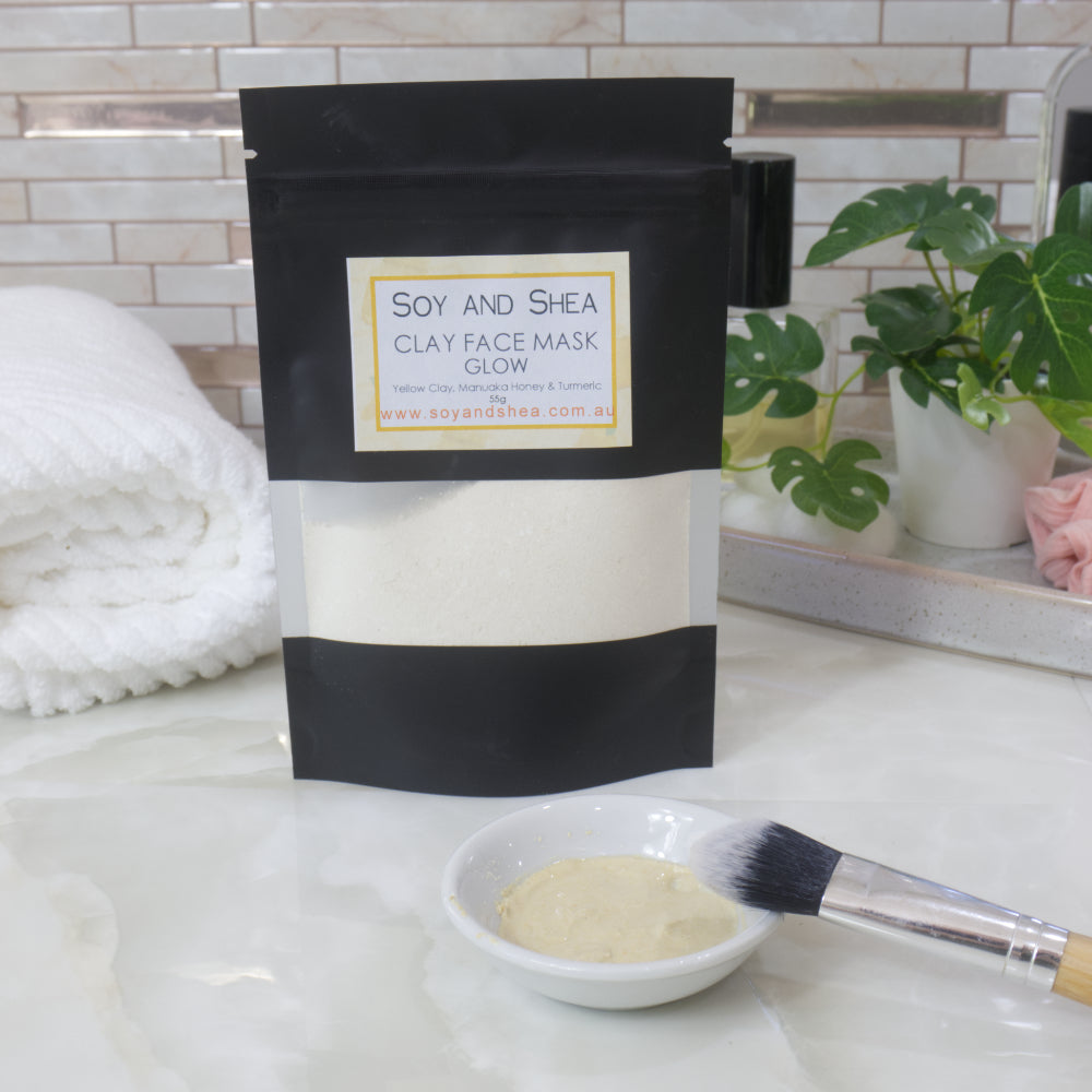 Soy and Shea clay face mask packaging with a bowl of hyrdrated mask and brush on a marble surface.