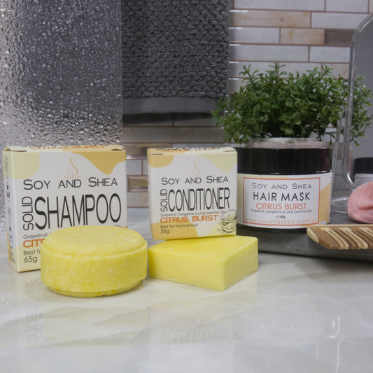 Soy and Shea hair care products including shampoo, conditioner, and hair mask on a bathroom counter. All products are in shades of yellow.