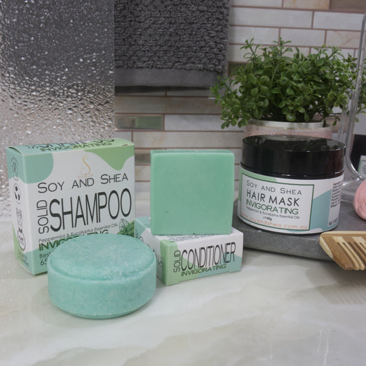 Soy and Shea hair care products including shampoo, conditioner, and hair mask on a bathroom counter. All products are in shades of green.