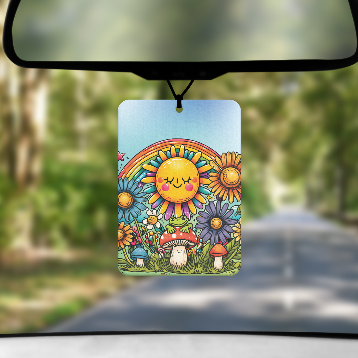 A mock up image showing a view through a car windscreen with a long tree lined road. From the rearview mirror hangs an air freshener with a cartoon image of a frog on a toadstool. above is s sun with smiley face and a rainbow all surrounded by flowers