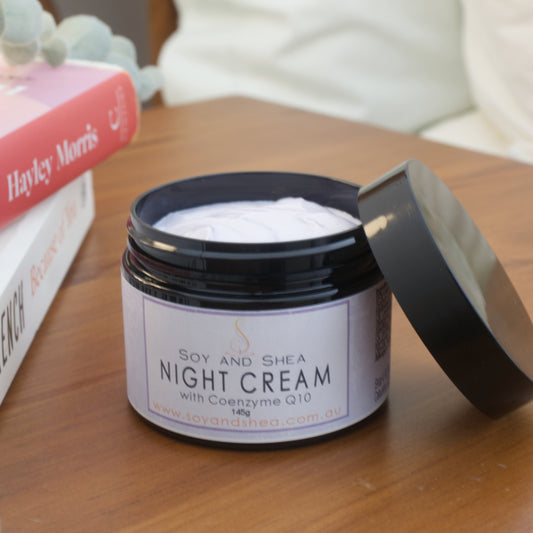 Jar of Soy and Shea Night Cream on a wooden nightstand with books in the background