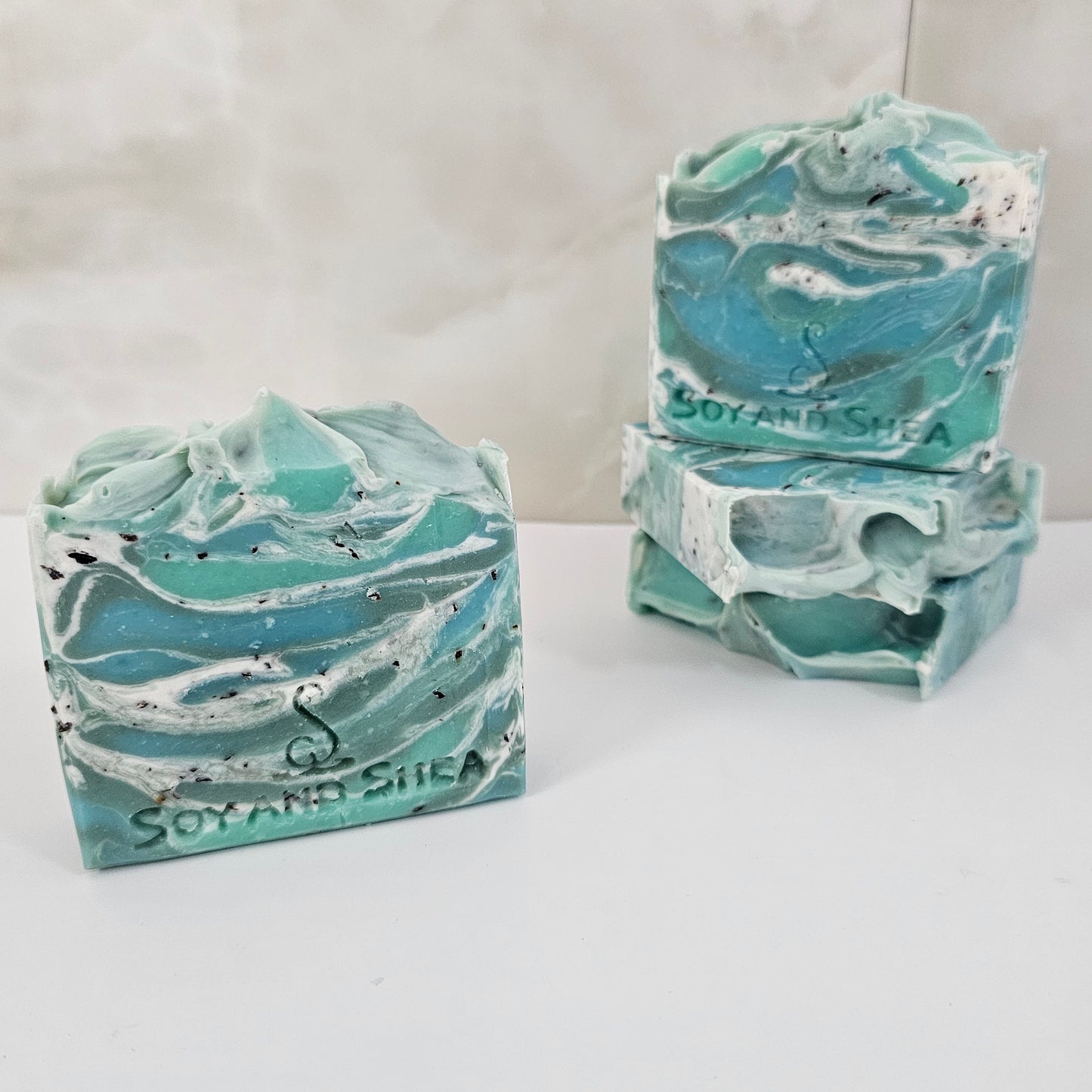 A selection of green and white marbled soap bars surrounded by white tiles. Two soaps show differing patterns to the soap