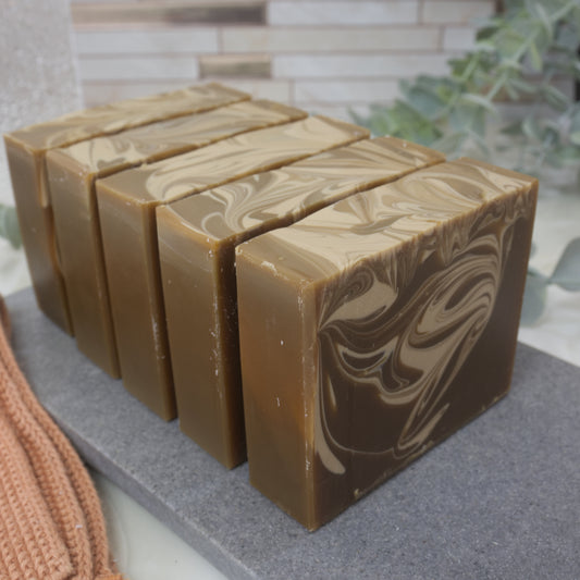 Row of brown soap bars with a marbled cream pattern on a gray surface.