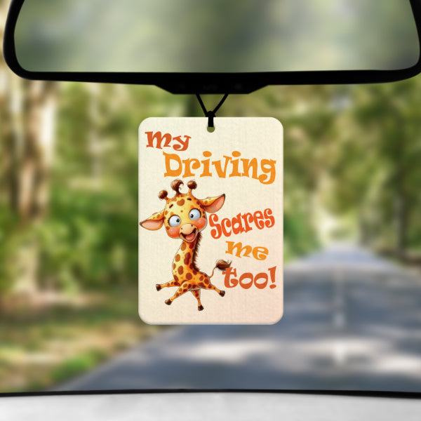 A mock up image showing a view through a car windscreen with a long tree lined road. From the rearview mirror hangs an air freshener with the words MY DRIVING SCARES ME TOO in tones of orange with a cartoon giraffe with a crazy look.