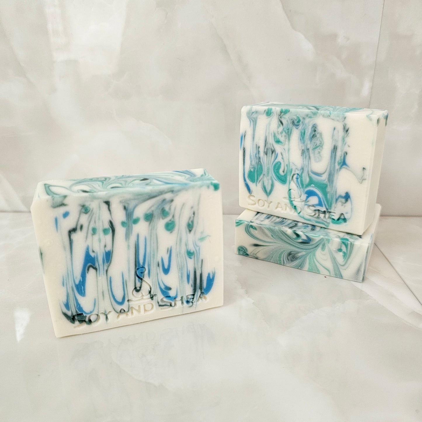 A selection of white bars of soap with blue and green drops of colour