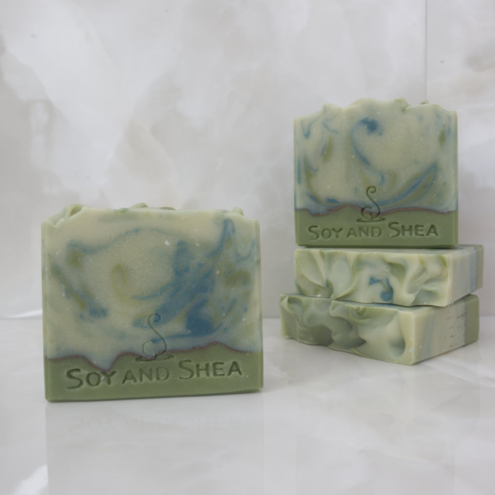 A selection of Soap Bars sit on a marble top. The soaps have varying shades of green swirls.