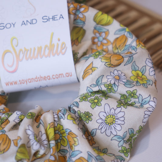 A close up of the fabric design on the Tulips Scrunchie highling the orange/yellow tulips and white daisies on a cream background.