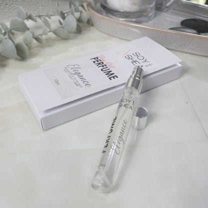 A tall, narrow clear perfume bottle with silver atomiser lays resting on its white boxed packaging with a silver cap next to it.  The box identifies it as Dry Oil Perfume in Elegance and 10ml