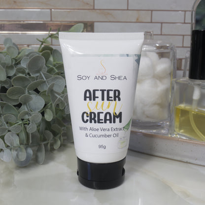 A white tube with black flip top cap sits on a marble bathroom countertop surrounded by greenery, a jar of cotton balls and bottle of perfume.  The tube is labelled as After Sun Cream