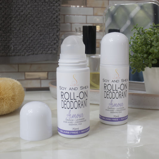 Two white bottles of Roll-On Deodorant stand upright on a bathroom counter top.  The bottle to the right features a domed lid, while the one to the left has had the lid removed showing a ball roller for application