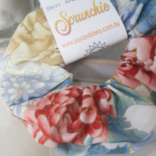 A close up image of the Big Bloom Scrunchie showing teh pattern detail.  The fabric has various styles of large flowers in shades of red, blue and gold