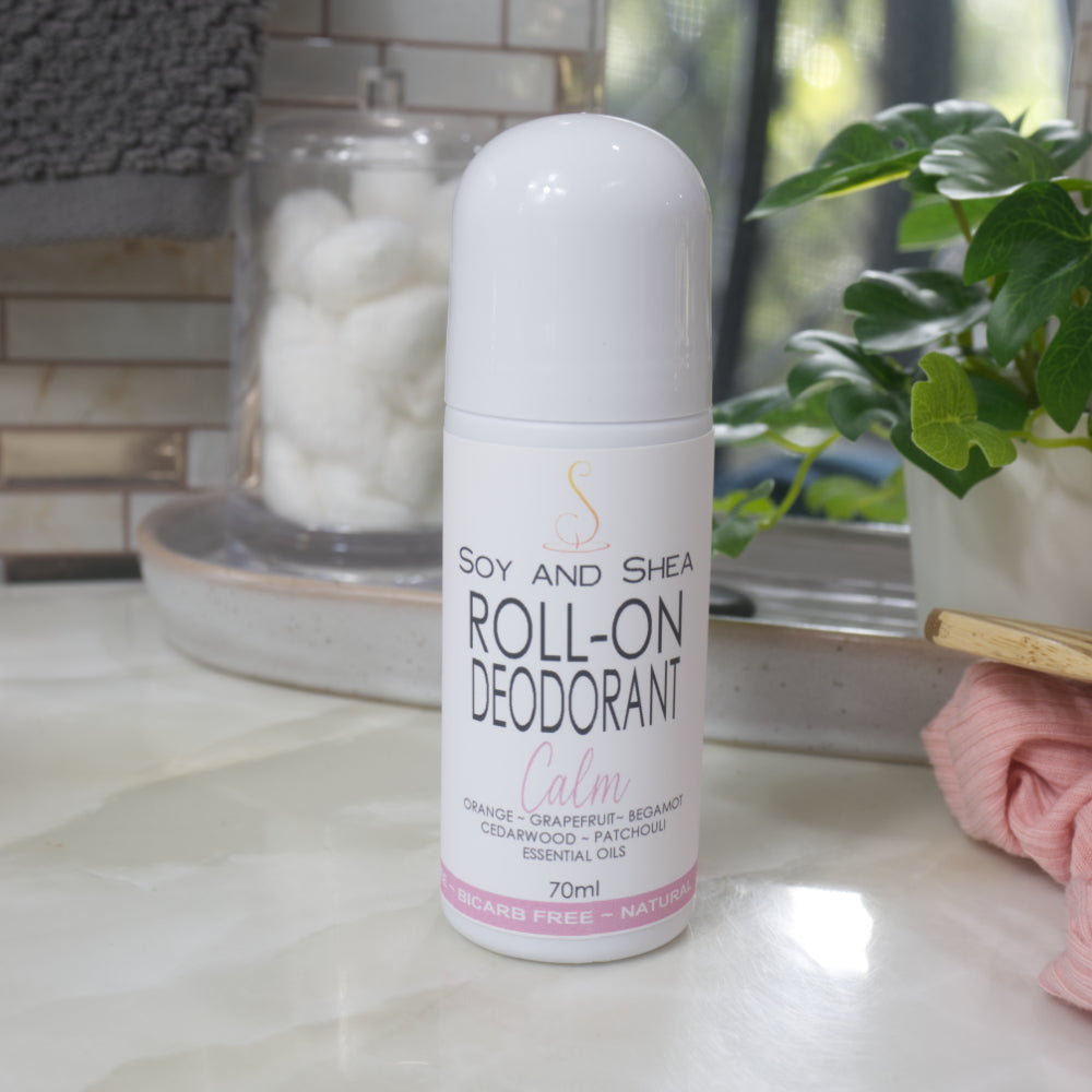 A white bottle with deocrative product label stands on a bathroom counter top.  The bottle is tall with a dome shaped cap.