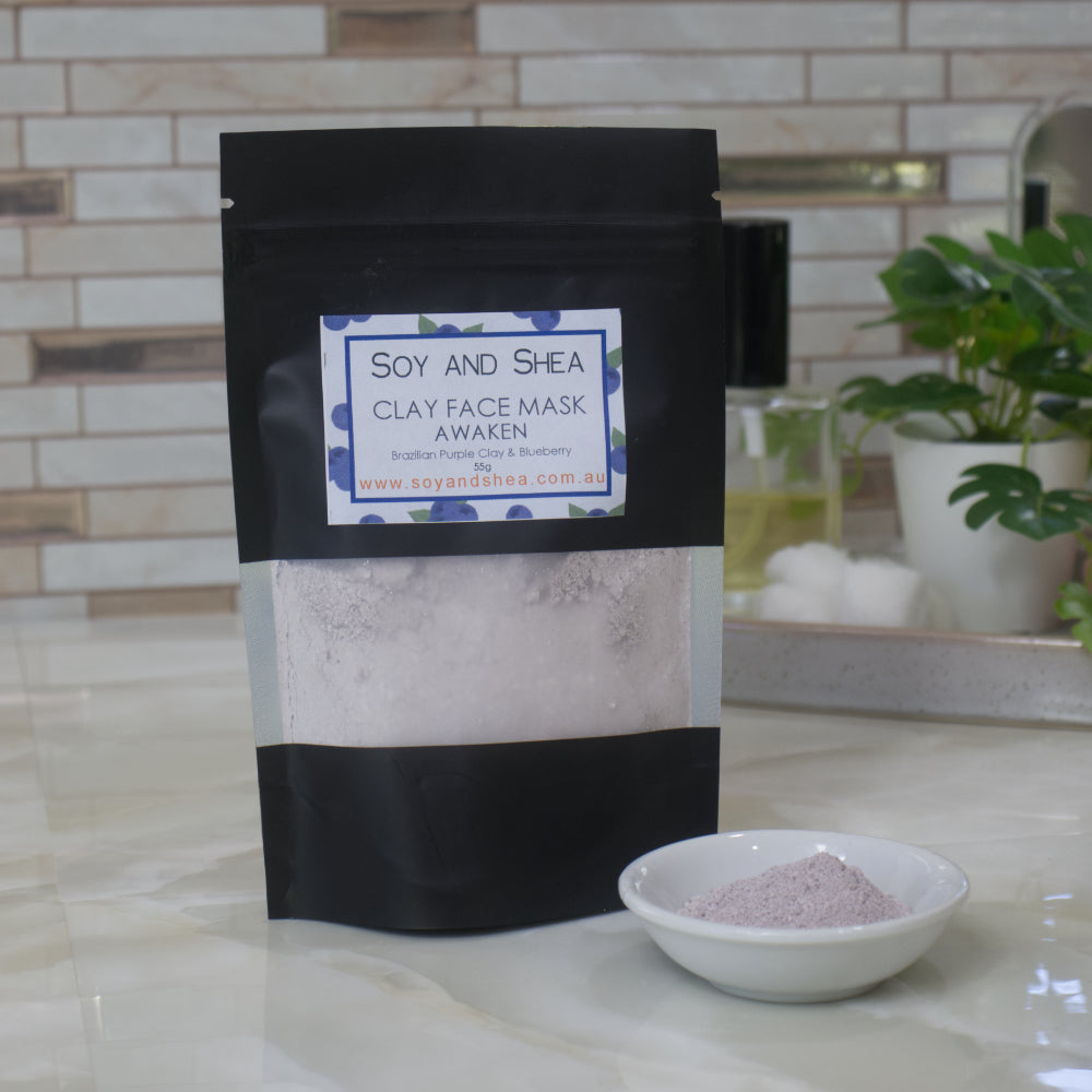 Soy and Shea Awaken Clay Face Mask packaging with a bowl of powder on a marble surface.