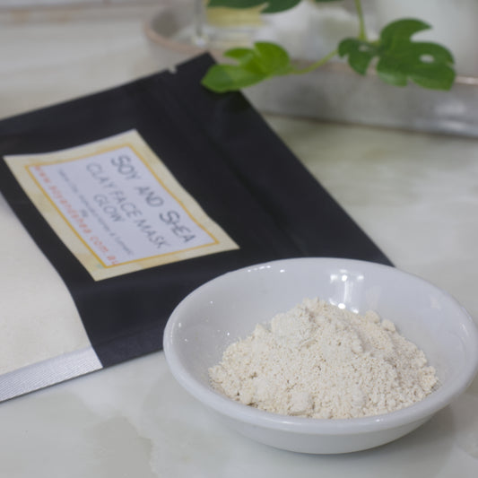 Yellow powder in a bowl with a black bag labeled 'Soy and Sea Clay Mask' on a light surface.