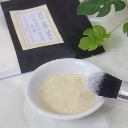 Soy and sea hydrated clay face mask in a small white bowl with a brush and packaging on a white surface.