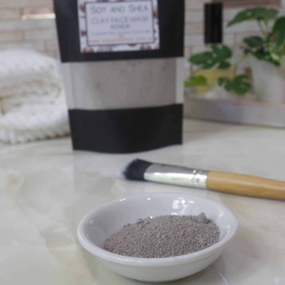 Soy and Shea clay face mask in a bowl with a brush and packaging in the background.
