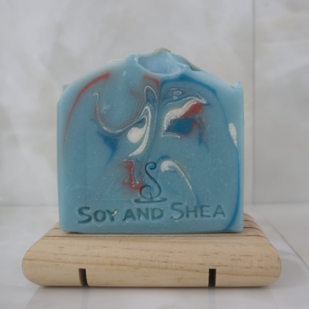 Blue marbled soap bar on a wooden stand with 'Soy and Shea' branding.