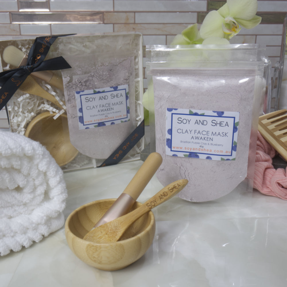 Soy and Shea Awaken Clay Face Mask packaging with a wooden spoon on a marble surface.