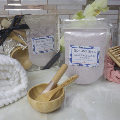 Soy and Shea Awaken Clay Face Mask packaging with a wooden spoon on a marble surface.