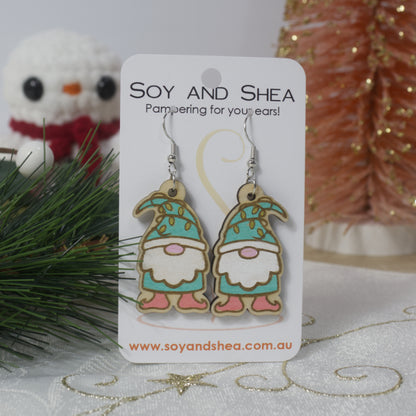 Gnome-themed earrings on a 'Soy and Shea' branded card with decorative background.  The earrings are wooden with Teal coloured gnomes