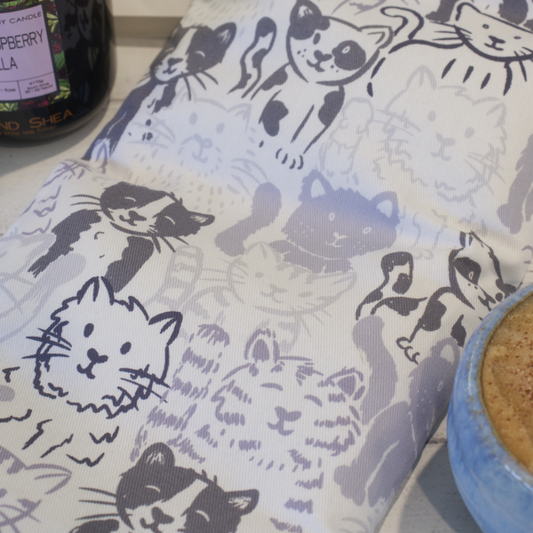 A close image of the fabric design of the Grey Cats Heat Pack.  It features pencil drawings of a variety if cats in various shades of grey on a white background.