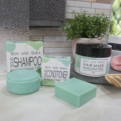 Collection of soy and shea hair care products on a bathroom counter. All products are in shades of green.