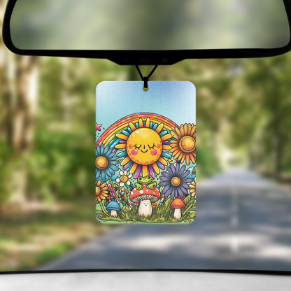 A mock up image showing a view through a car windscreen with a long tree lined road.  From the rearview mirror hands an air freshener with a cartoon image of a frog on a toadstool.  above is s sun with smiley face and a rainbow all surrounded by flowers