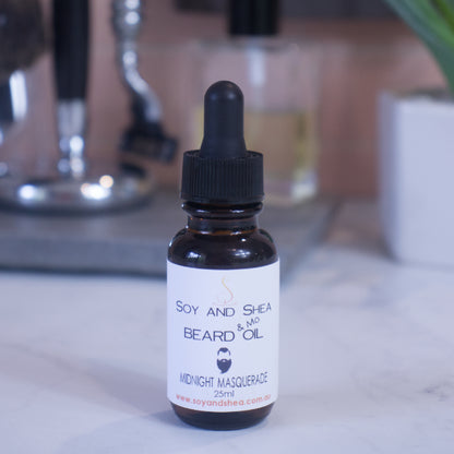 A small brown bottle with a dropper lid, labeled "Soy and Shea Midnight Masquerade Beard & Mo Oil," sits on the marble surface with shaving accessories on a blurred background