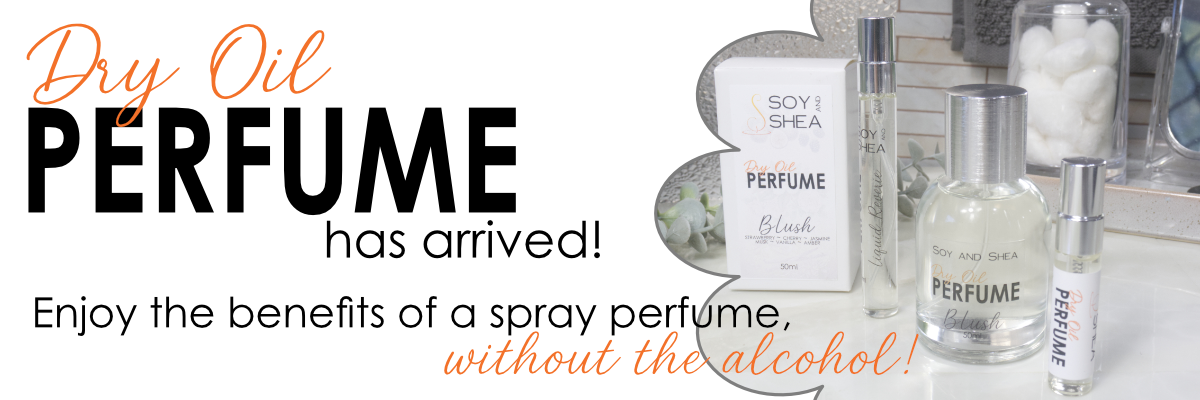 Promotional banner for Soy and Shea Dry Oil Perfume, showing a clear spray bottle, a small cylindrical atomizer, and a boxed perfume on a countertop with large text reading 'Dry Oil PERFUME has arrived! Enjoy the benefits of a spray perfume, without the alcohol!'.