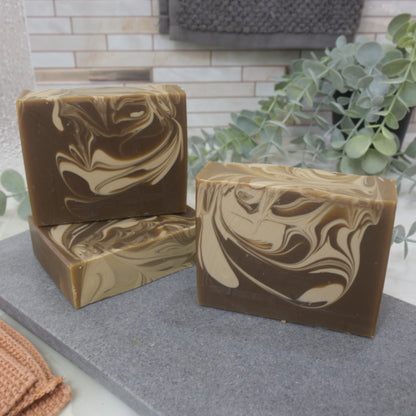 Three swirled brown and beige soap bars on a gray surface with a blurred background