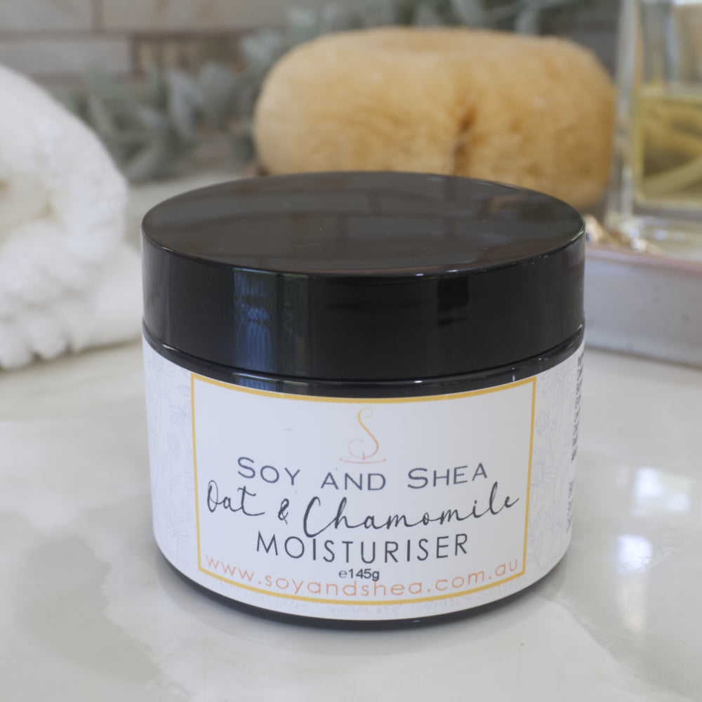 A jar with black lid and decorative product label in shades or white and yellow stands on a marble surface with a blurred background.