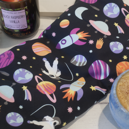 A close up shot of the Outer Space Heat packing showing the fabric design which has a black background featuring colorful space-themed patterns, including planets and rockets, and a white astronaut.