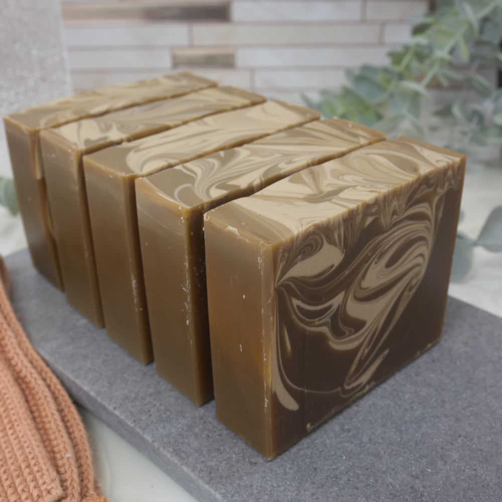 Row of brown soap bars with a marbled  cream pattern on a gray surface.