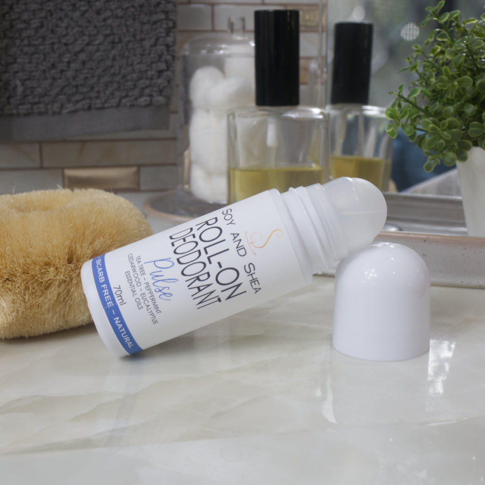 A white bottle of Pulse Roll-On Deodorant lays on its side with the top propped up by the lid which has been removed to reveal a ball roller for application