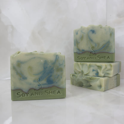 A selection of Soap Bars sit on a marble top.  The soaps have varying shades of green swirls.