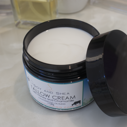 An overhead shot of a black jar of Tallow Cream with the lid off and restiing on the side.  The jar is filled with a white cream