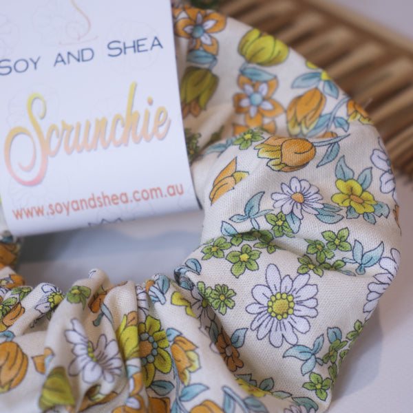 A close up of the fabric design on the Tulips Scrunchie highling the orange/yellow tulips and white daisies on a cream background.