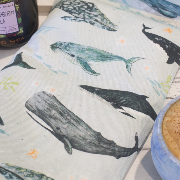 A close up photo of the Whales Heat Pack showing watercolour drawings of various whales over a light blue background