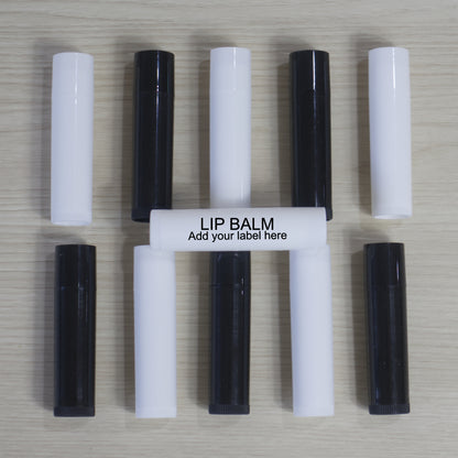 Two rows of five lip balm tubes lie on a wooden surface alternating between white and black.  A white tube lies across this with text of "Lip Balm.  Add your label here"
