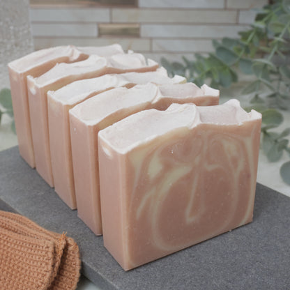 Row of soap bars with a pink and white marbled design on a gray surface, with a blurred background.