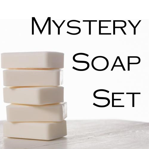 A stack of 5 white soaps sit on a wooden surface against a bright white backgroud with the text MYSTERY SOAP SET